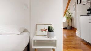A bedroom with a bed, a bedside table with a framed picture, and a potted plant. - Arriaga River Views II (Lisbon)