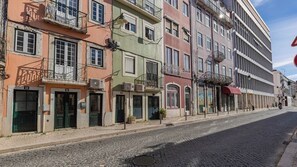 A cobblestone street lined with multi-story buildings, some with balconies and air conditioning units. - Arriaga River Views II (Lisbon)