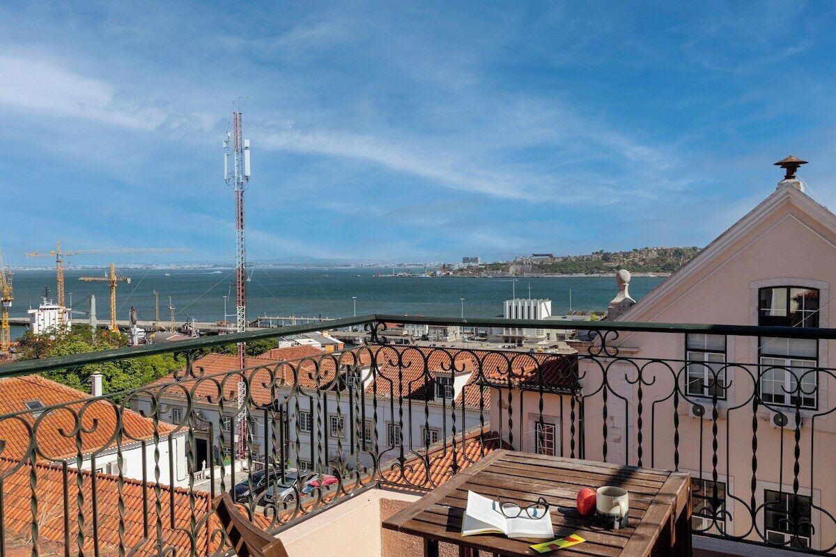 A balcony with a view of the sea, construction cranes, and buildings in the background.