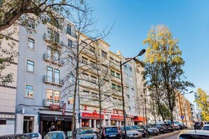 A multi-story building with balconies, storefronts, and parked cars. - Double Bedroom @ Guest Inn 1 Boutique House (campo pequeno)