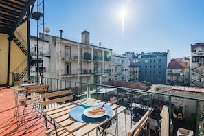 A balcony with wooden furniture, a pizza on a plate, and a view of surrounding buildings. - Double Bedroom @ Guest Inn 1 Boutique House (campo pequeno)