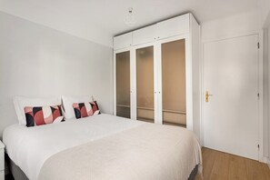 Ein Schlafzimmer mit einem Bett, einem Schrank mit Milchglasschränken und einer Tür mit Griff.
