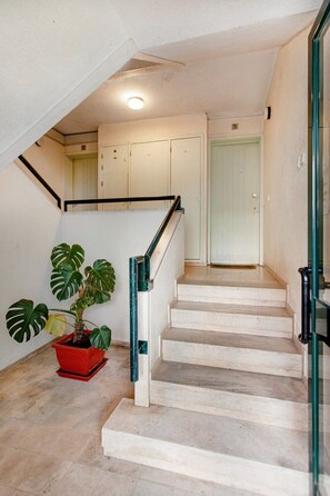 A staircase with a handrail, a potted plant, and a door at the top. - WFH Urban Retreat @ Carnide (Lisbon)