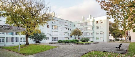 Une cour intérieure avec un bâtiment à l’architecture moderne, un chemin pavé et un banc.