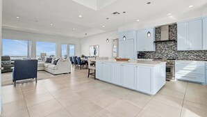 Una cocina moderna con armarios azul claro, una isla central y un salpicadero de piedra.