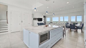 Una cocina amplia con una isla grande, iluminación colgante moderna y un comedor con vistas.