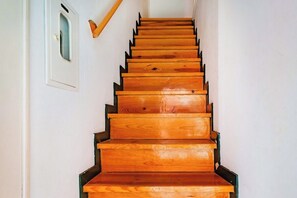A wooden staircase with a handrail and a wall-mounted light fixture. - Alfama Comfy Studio (Lisbon)