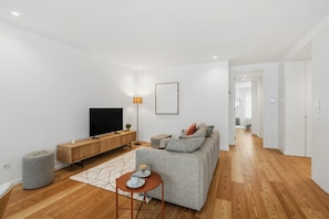 A modern living room with a flat-screen TV, a sofa, a coffee table, and a lamp. - Sal D'Ouro | Terrace & Beach (Vila Nova de Gaia)