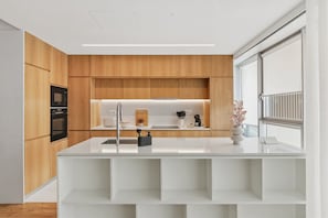 A modern kitchen with wooden cabinetry, a white countertop, and built-in appliances. - Sal D'Ouro | Terrace & Beach (Vila Nova de Gaia)