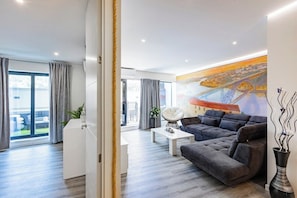A modern living room with a grey sofa, a white coffee table, and a large painting of a bridge. - Porto City Holidays by Douro River (Porto)