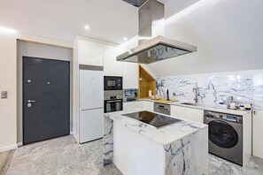 A modern kitchen with a central island, built-in appliances, and a marble backsplash. - Porto City Holidays by Douro River (Porto)