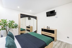 A bedroom with a bed, a mirror, a TV, a plant, and a dresser. - Porto City Holidays by Douro River (Porto)