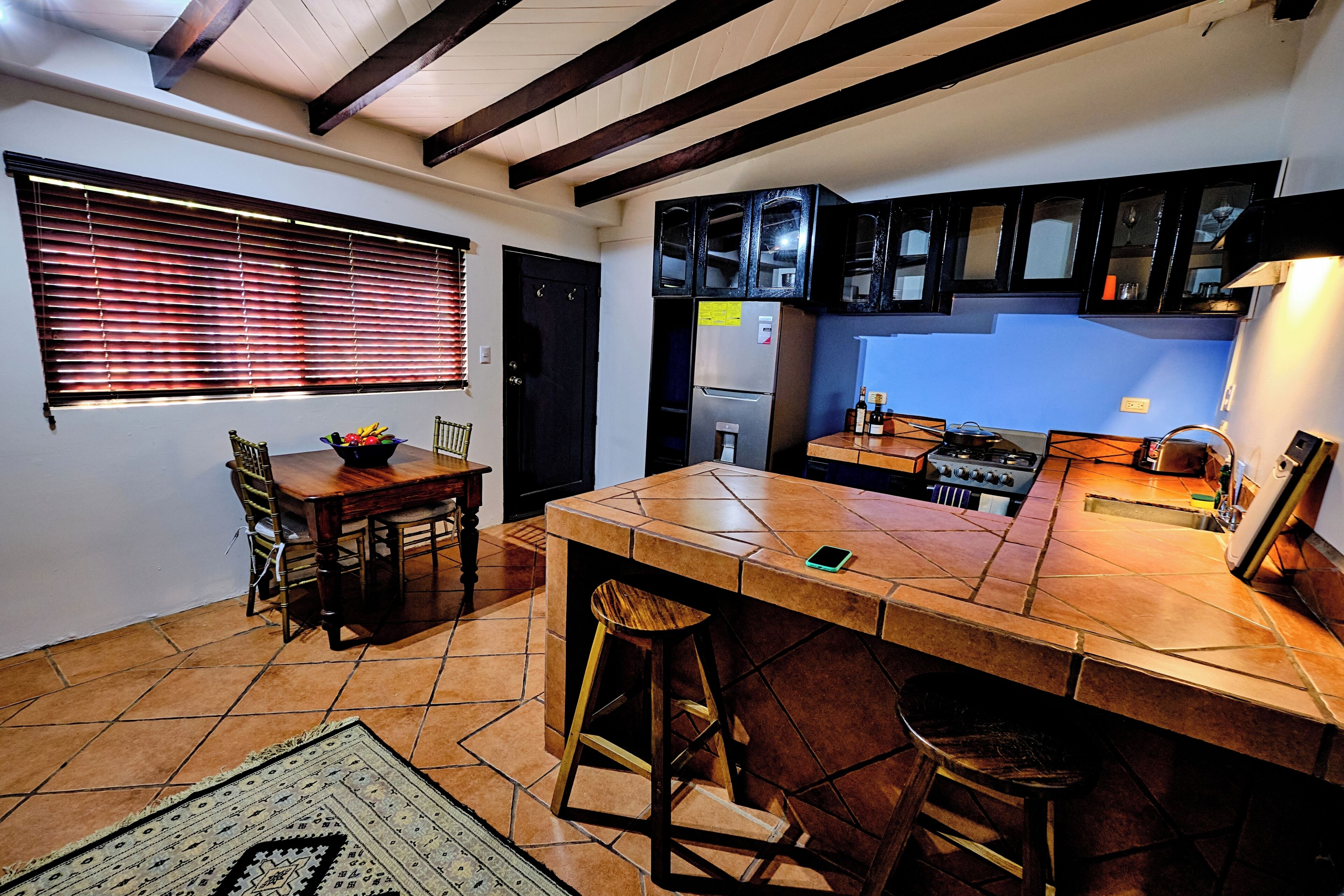 A kitchen with a dining area, a refrigerator, a stove, and a window with blinds.