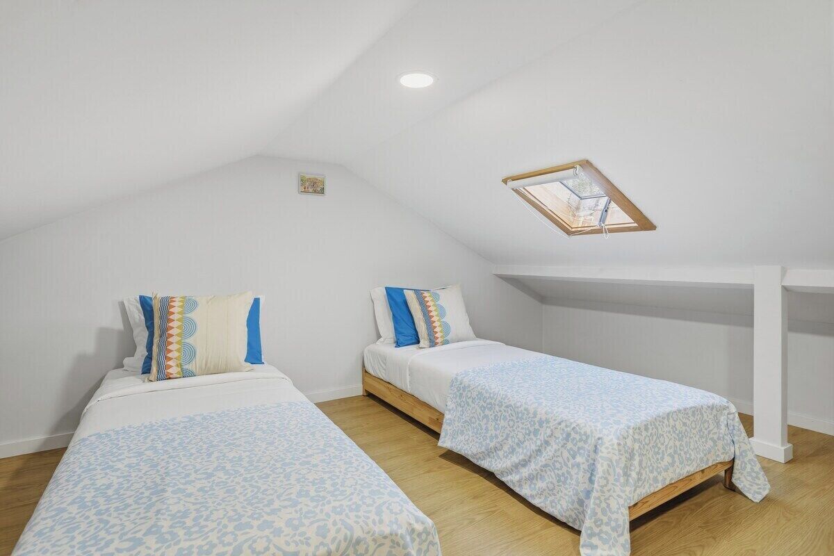 Une chambre avec deux lits, une lucarne et un plancher en bois.