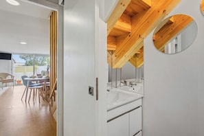 A modern bathroom with a wooden ceiling, a round mirror, and a white sink. - Sunny House with Private Terrace | Gaia (Vila Nova de Gaia)