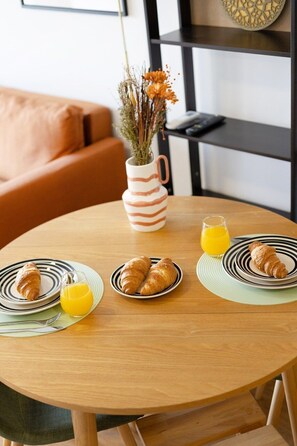 A breakfast setting with croissants, orange juice, and a vase with dried flowers on a round wooden table. - Sunny House with Private Terrace | Gaia (Vila Nova de Gaia)