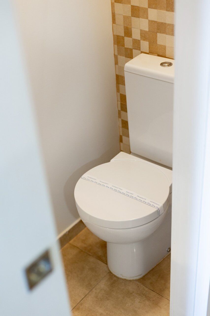A white toilet with a checkered tile wall behind it.