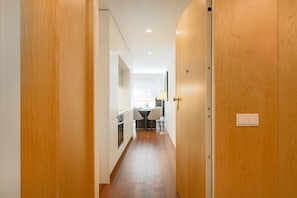 Ein Flur mit Holztüren, eine Küchenzeile mit Esstisch und eine Decke mit Einbaustrahlern.