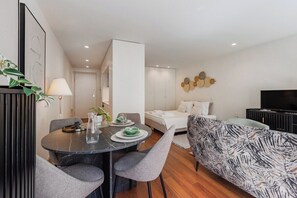 Een moderne hotelkamer met een zithoek, een bank, een televisie en een muur met decoratieve objecten.