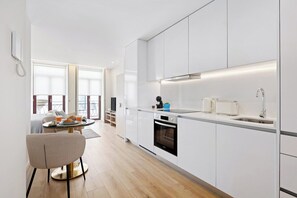 Una cocina moderna con armarios blancos, horno empotrado y pileta de acero inoxidable.