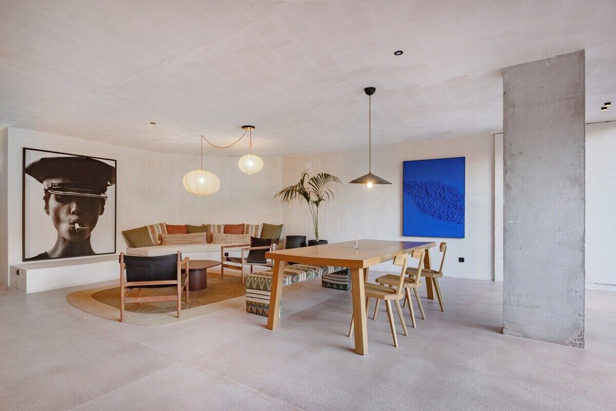 Een moderne woonkamer met een houten eettafel, een bank en een groot abstract schilderij aan de muur.