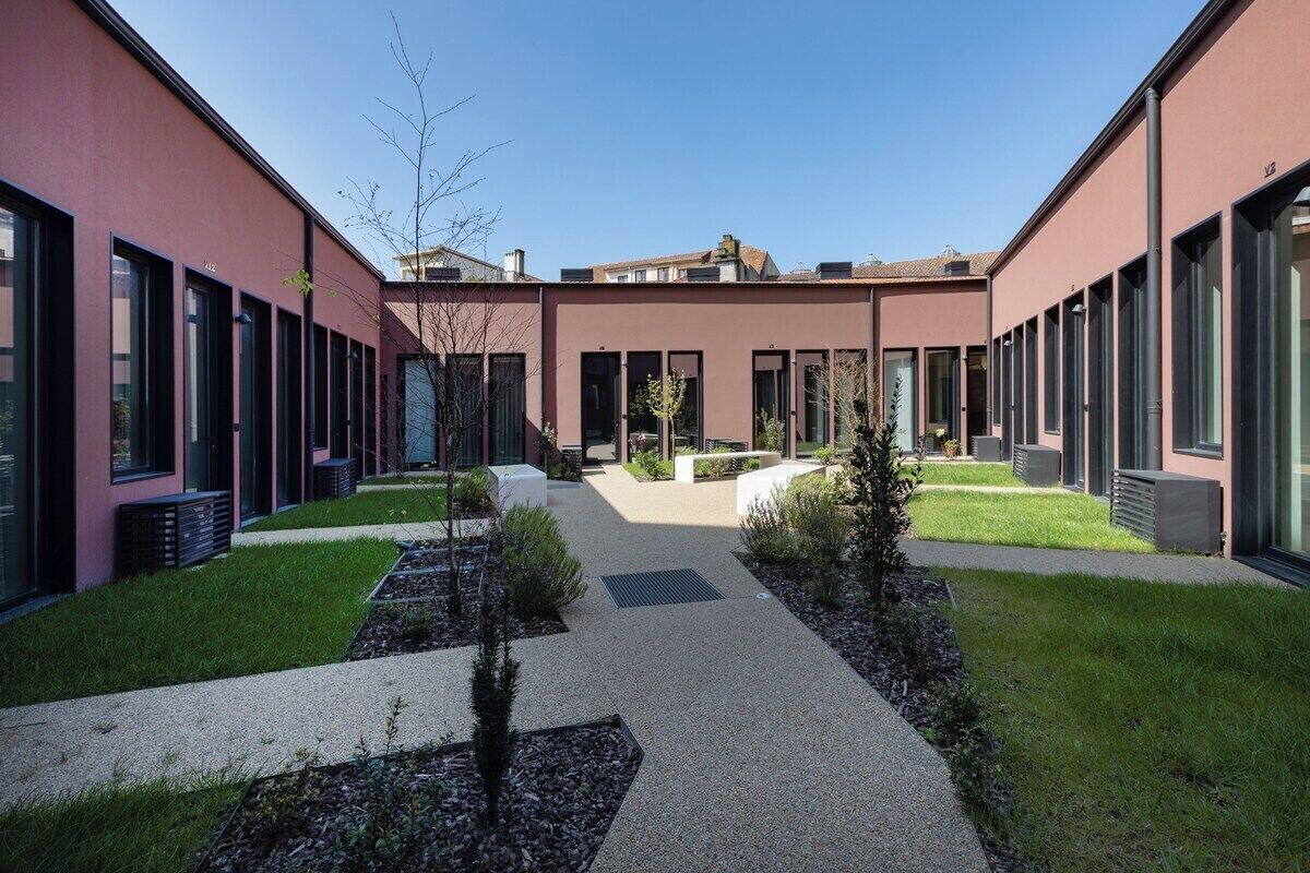 A courtyard with modern buildings, a central pathway, and small plants.