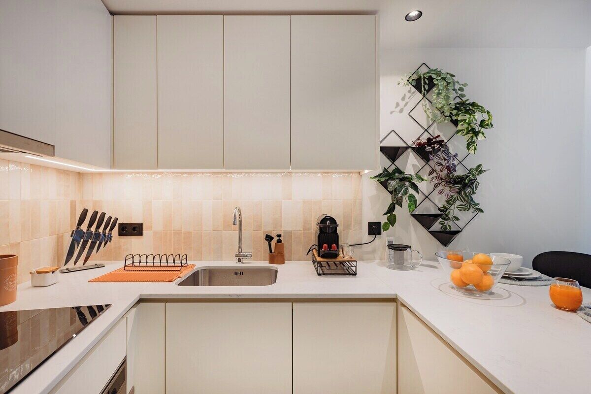A modern kitchen with a central island, a built-in oven, and a wall-mounted plant display.