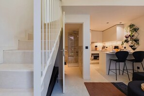 A modern interior with a staircase, a kitchen with bar seating, and a visible bathroom. - Urban Loft @ Terracotta Collection (Porto)