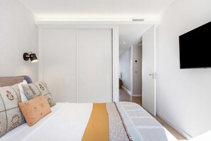 Ein Schlafzimmer mit Bett, Kissen, einer Nachttischlampe, einem Fernseher und einem Kleiderschrank.