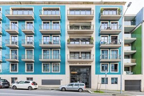 Ein mehrstöckiges Gebäude mit Balkonen, ein Ladenlokal mit der Aufschrift 'PORTO RENOVATO' und abgestellte Autos.