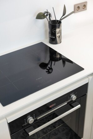 A kitchen with a black induction cooktop and a built-in oven. - Avenue 104 @ Porto Renovato, Bonfim (Porto)