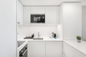 Une cuisine moderne équipée d’un four à micro-ondes encastré, d’un évier en acier inoxydable et d’une machine à café.