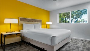 Ein Hotelzimmer mit einem Bett, zwei Nachttischen und einem Fenster mit Jalousien.