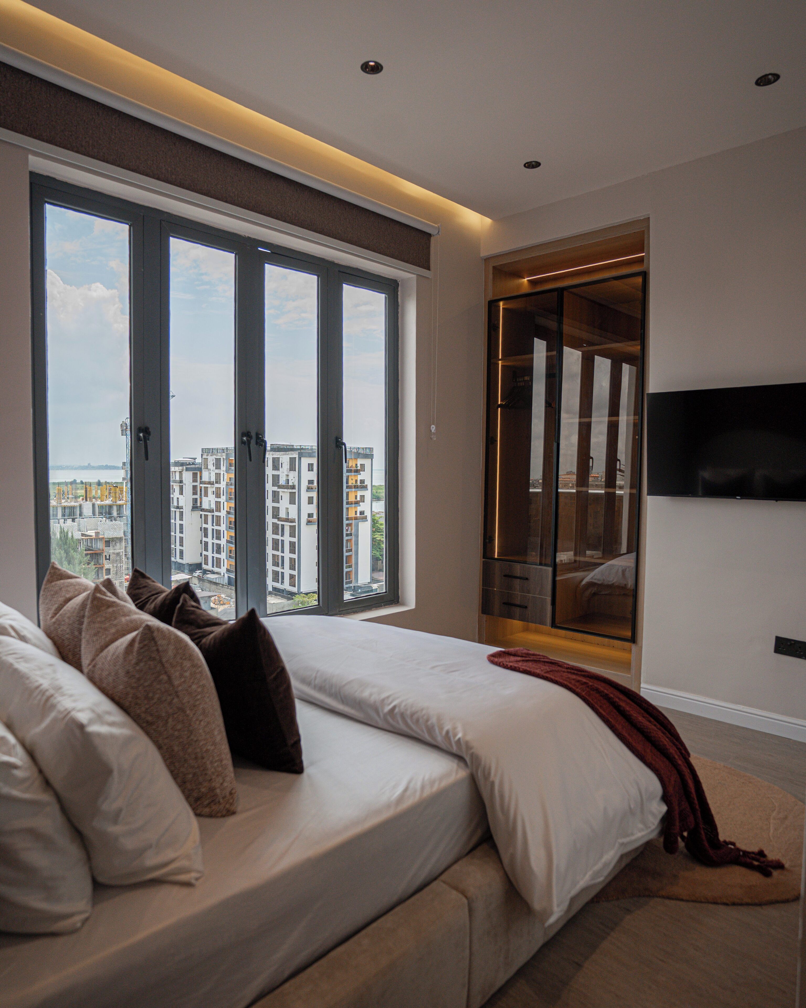 A modern bedroom with a large bed, a wardrobe, and a TV.