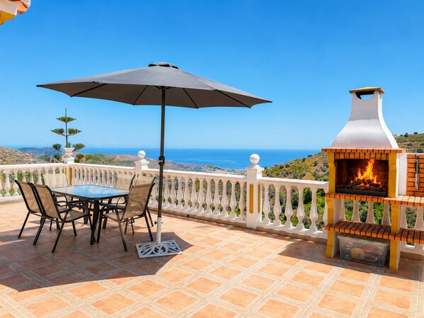 A terrace with a table and chairs, a grill, and a view of the sea. - Villa Cecilia con Vistas by At Home Costa del Sol (Torrox)