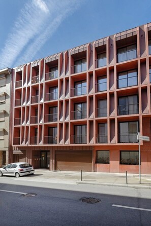 A multi-story building with a grid-like facade, balconies, and a car parked in front. - Bonfim Loft with Mezzanine | Terracotta Collection (Porto)