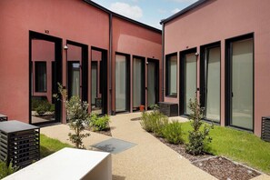 A modern building with large glass doors and windows, a paved courtyard with small plants, and a metal grate. - Bonfim Loft with Mezzanine | Terracotta Collection (Porto)