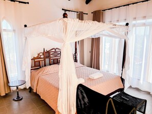 A room with a four-poster bed, a round table, and a chair. - Villa Mbingu - Beach Front Villa (Kilifi)
