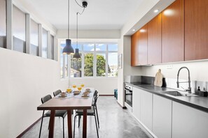 A modern kitchen with a dining area, large windows, and a view of the city. - Porto Unik | Walk to Historical Center (Porto)