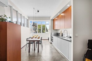 A modern kitchen with a dining area, large windows, and a view of greenery outside. - Porto Unik | Walk to Historical Center (Porto)