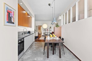 A modern kitchen with a dining area, a pendant light, and a view into the living space. - Porto Unik | Walk to Historical Center (Porto)