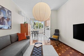 A modern living room with a sofa, a dining table, and a TV. - Porto Unik | Walk to Historical Center (Porto)