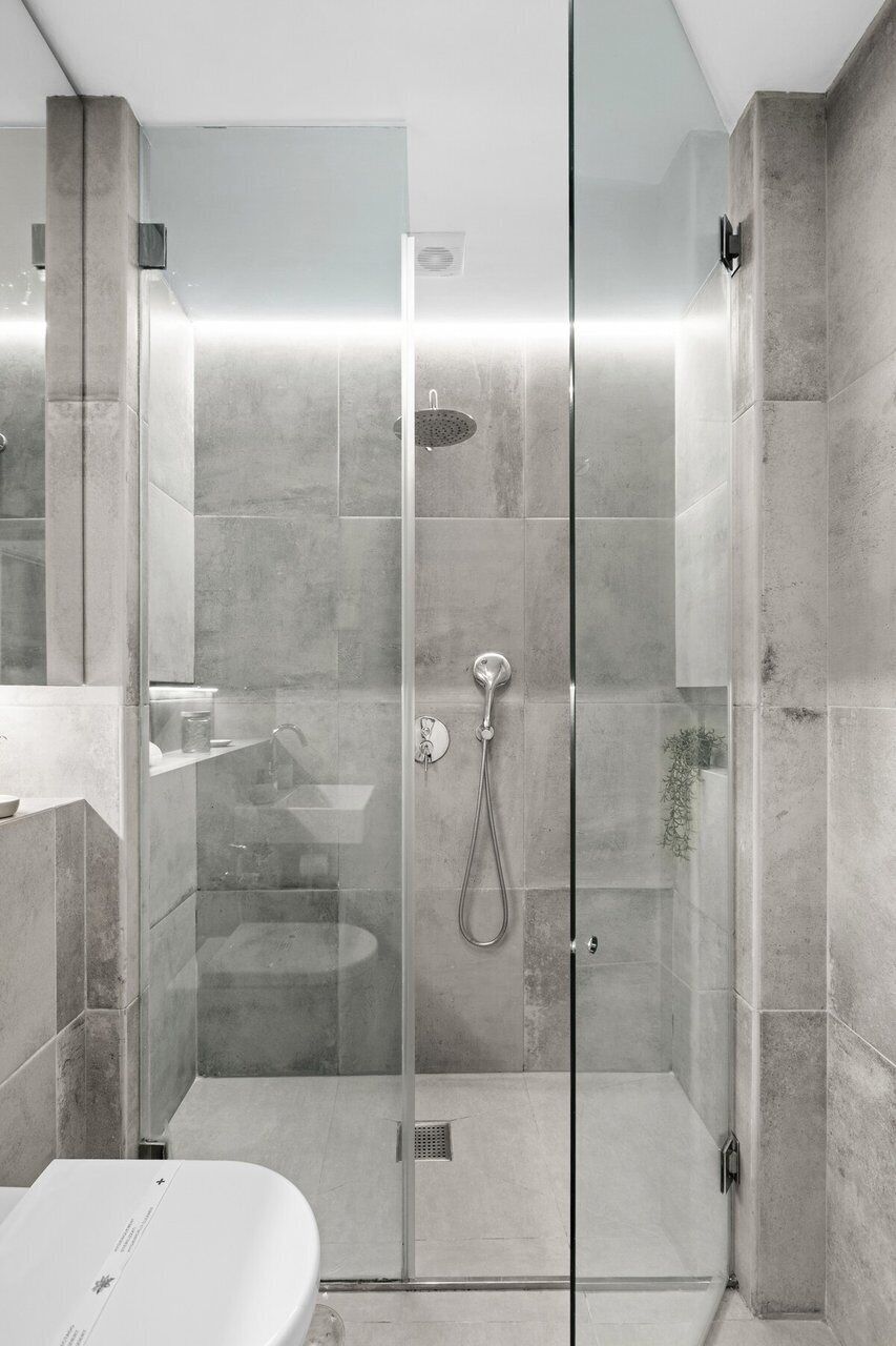 Ein modernes Badezimmer mit einer Duschkabine aus Glas, einem weißen Waschbecken und einer Toilette.