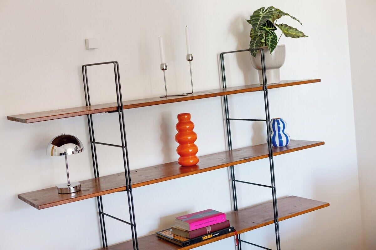 A wall-mounted shelving unit with three shelves, a potted plant, and decorative items.