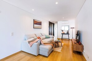 A modern living room with a sofa, a small side table, and a wooden sideboard. - Camões Downtown with Parking (Porto)