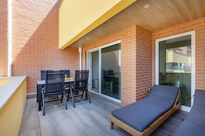 A small outdoor patio with a table and chairs, a single bed, and a sliding glass door leading to an indoor area. - The Pine Flat with Pool @ Furadouro (Ovar)