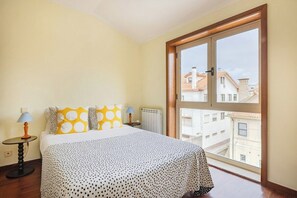 Ein Schlafzimmer mit Bett, Fenster, Lampe und Heizkörper.