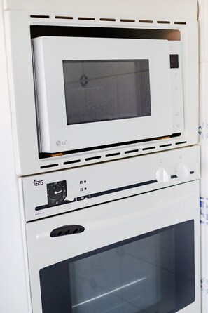Une cuisine équipée d’un four à micro-ondes, d’un four traditionnel et d’une horloge.
