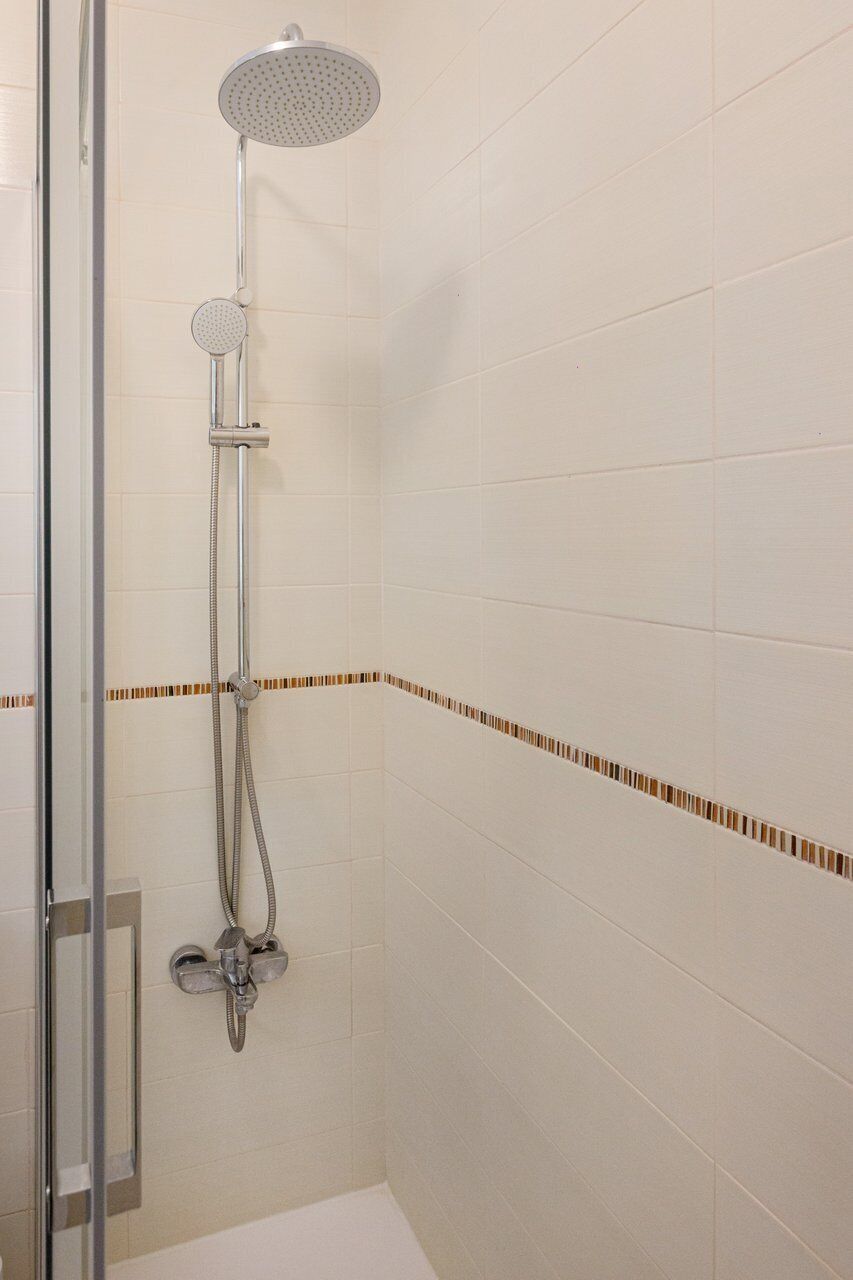 A shower with a handheld showerhead, a fixed showerhead, and a handheld shower attachment.