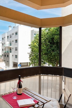 A balcony with a table, a bottle of wine, and a glass, overlooking a building and trees. - The Cascais Hideaway (Cascais)